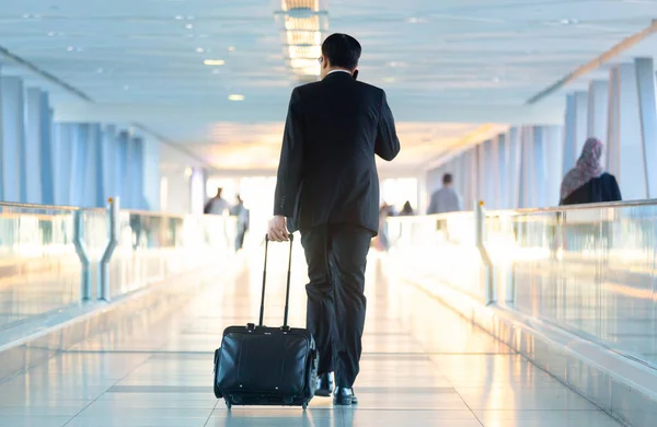 Uomo d'affari che cammina e porta una valigia del carrello all'ingresso, parlando con un cellulare. Business travel concept . — Foto Stock