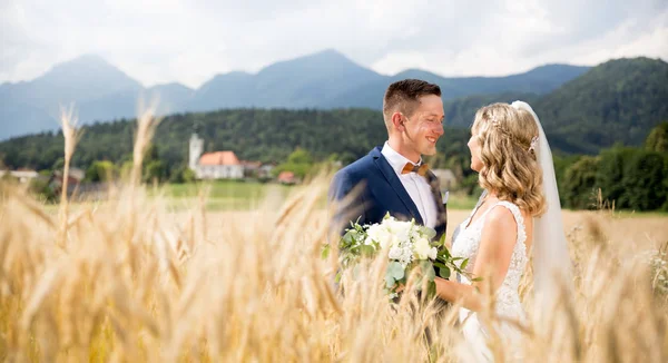 Наречений обіймає наречену ніжно в пшеничному полі десь в словенському сільській місцевості. — стокове фото