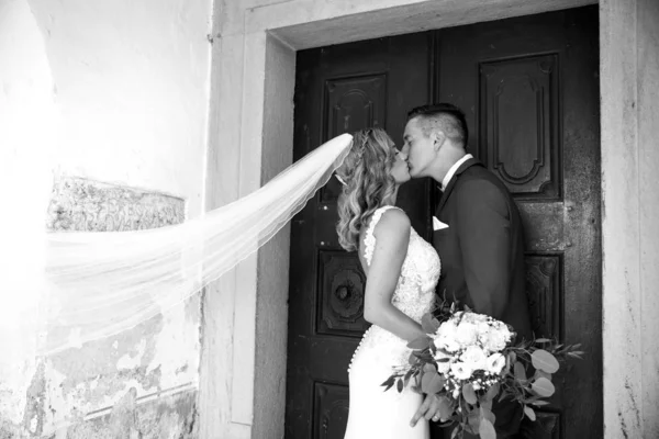 El beso. Novia y novio besos tiernamente delante del portal de la iglesia . — Foto de Stock