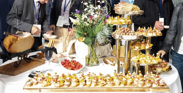 Empresários na pausa para o almoço do banquete na conferência de negócios. Sortimento de canapés e comida para os dedos na mesa. — Fotografia de Stock