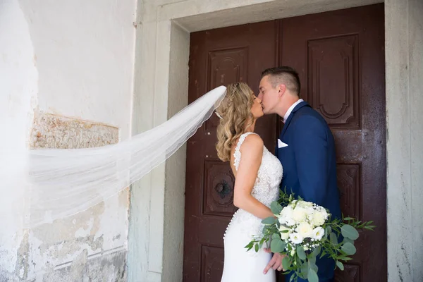 Le baiser. Mariée et marié embrasse tendrement devant le portail de l'église . — Photo