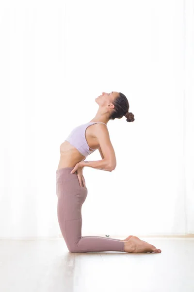 Retrato de linda jovem desportiva ativa praticando ioga no estúdio. Menina bonita praticar Ustrasana, pose de ioga de camelo. Estilo de vida ativo saudável, exercitando-se dentro de casa no ginásio — Fotografia de Stock