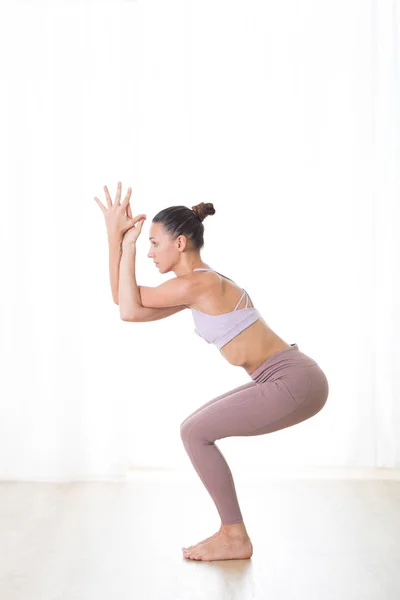 Portret wspaniałej aktywnej sportowej młodej kobiety ćwiczącej jogę w studio. Piękna dziewczyna ćwiczy Garurasanę, pozuje na jogę orła. Zdrowy aktywny tryb życia, ćwiczenie wewnątrz sali gimnastycznej — Zdjęcie stockowe