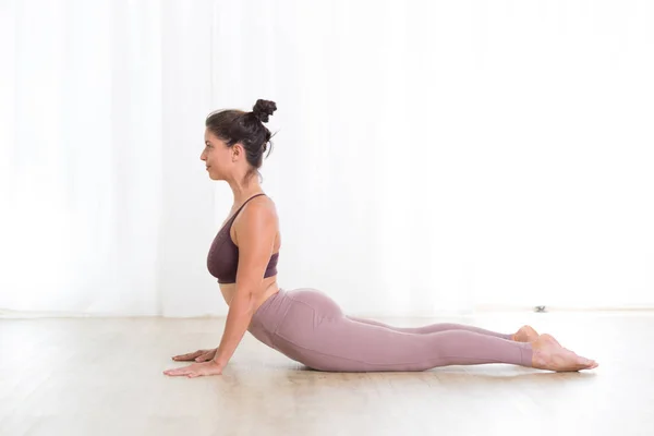 Portret van een prachtige actieve sportieve jonge vrouw die yoga beoefent in de studio. Mooi meisje praktijk Sasangasana, konijn yoga pose. Gezonde actieve levensstijl, sporten in de fitnessruimte — Stockfoto