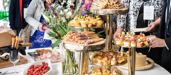 Empresários na pausa para o almoço do banquete na conferência de negócios. Sortimento de canapés e comida para os dedos na mesa. — Fotografia de Stock