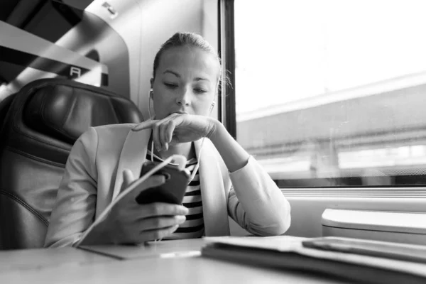 Bizneswoman komunikujących się przez telefon komórkowy podczas podróży pociągiem. — Zdjęcie stockowe