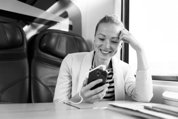 Geschäftsfrau kommuniziert auf Bahnreise per Handy. — Stockfoto