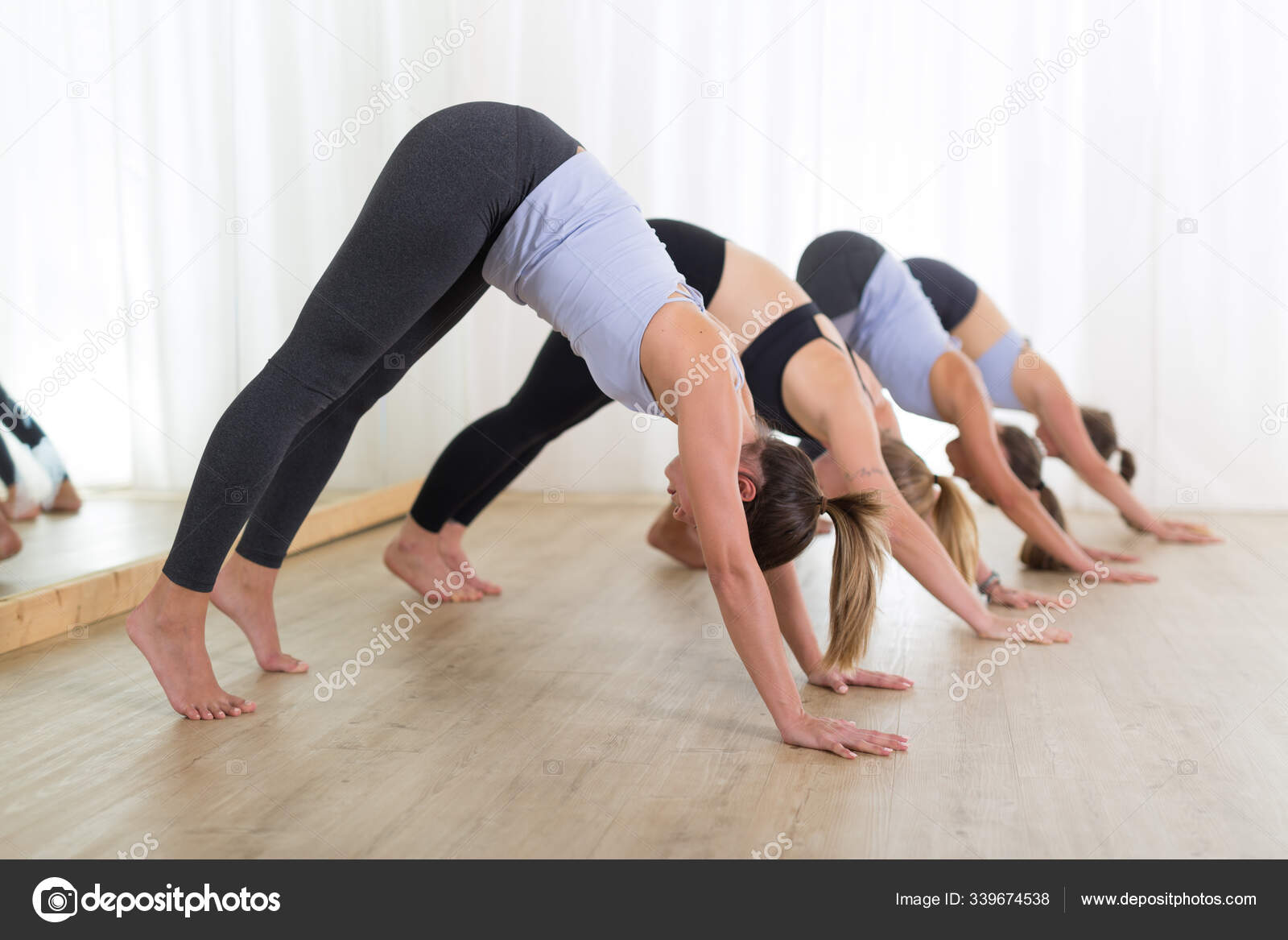 Group of young sporty sexy women in yoga studio, practicing yoga lesson  with instructor, forming a
