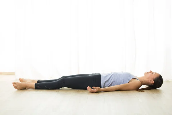 Portrait of gorgeous active sporty young woman practicing yoga in studio. Beautiful girl relaxing in Savasana, corpse pose. Healthy active lifestyle, working out indoors in gym — Stock fotografie