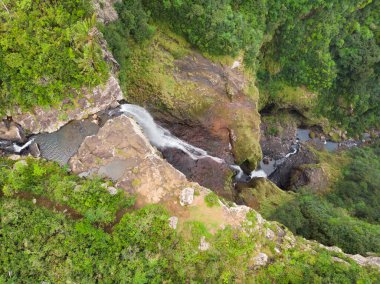 Mauritius adasında Kiyabir adasındaki Black River Gorges milli parkının tropik ada ormanında 500 feet'lik şelalenin kenarında duran, drone'a el sallayan seyahat çiftinin havadan görünümü