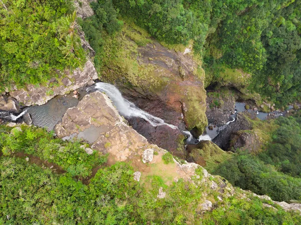 Εναέρια κορυφή θέα του ταξιδιωτικού ζευγαριού που χαιρετά το τηλεκατευθυνόμενο, στέκεται στην άκρη του καταρράκτη 500 ποδιών στη ζούγκλα του τροπικού νησιού του μαύρου ποταμού στο νησί του Μαυρικίου — Φωτογραφία Αρχείου