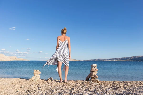 Heureuse femme insouciante profitant d'une promenade en fin d'après-midi sur une plage de galets blancs sur l'île de Pag, Croatie — Photo