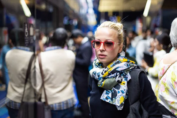 Молода жінка в барвистому шарфі чекає на платформі міської станції метро для прибуття поїзда. Громадський транспорт — стокове фото
