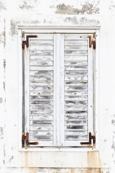 White weathered rusted wooden window shutters.