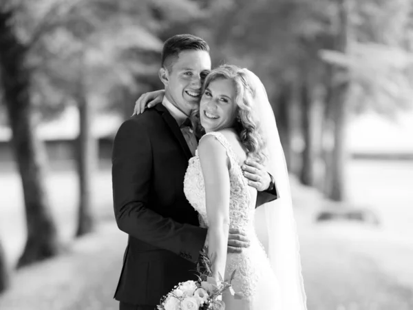 Menyasszony és vőlegény ölelés gyengéden pózol fotózás közben a parkban. — Stock Fotó