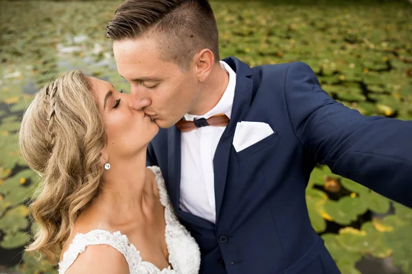 Hochzeit-Selfie. Braut und Bräutigam küssen sich leidenschaftlich im Park. — Stockfoto