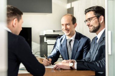 Bir grup başarılı iş adamı modern şirket ofisindeki iş toplantısında anlaşmayı imzalamak ve gözden geçirmek için bir sözleşme imzaladı..