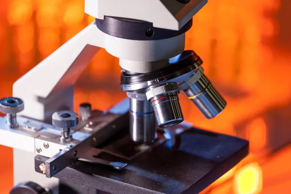 Primer plano de las lentes del microscopio centradas en una muestra con luz naranja cálida . — Foto de Stock