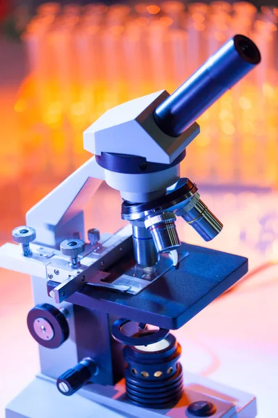 Close up of microscope lenses focused on a specimen in warm orange light light. — Stock Photo, Image