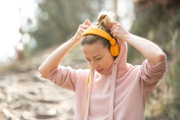 Portrait of beautiful sports woman with hoodie and headphones during outdoors training session. — Stock Photo, Image