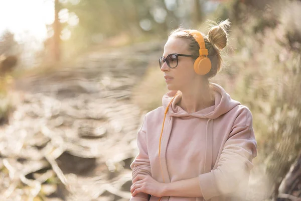 Portrait of beautiful sports woman wearing sunglasses, hoodie and headphones during outdoors training session — Stock Photo, Image