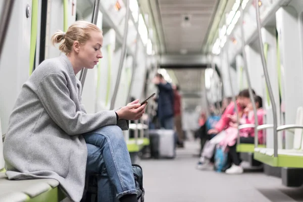 Neredeyse boş bir metro treninde cep telefonuna mesaj yazan güzel bir kızın portresi. Korona virüsü salgını yüzünden evde kalmak ve sosyal farklılıklar yeniden düzenlendi — Stok fotoğraf