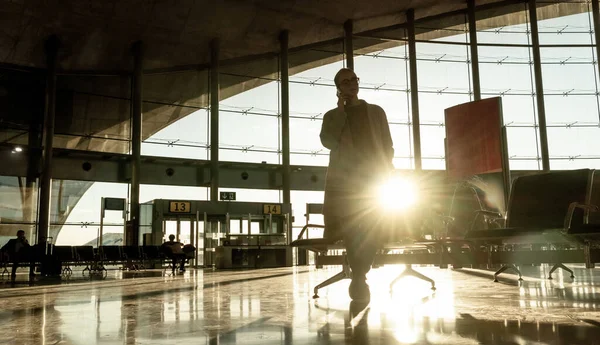 Silueta de mujer metida en la terminal del aeropuerto por cancelación de vuelos, llamando a la familia, sentada en una terminal del aeropuerto casi vacía debido a la pandemia de coronavirus, Covid 19, restricciones de viaje por brote —  Fotos de Stock