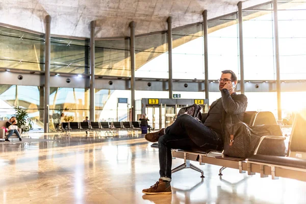 Jeune homme décontracté utilisant son téléphone portable en attendant de monter à bord d'un avion aux portes de l'aéroport. — Photo