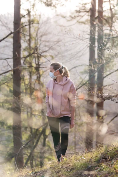 O vírus Corona, ou Covid-19, está se espalhando por todo o mundo. Retrato de mulher esportiva caucasiana vestindo uma máscara de proteção médica enquanto caminhava na floresta. Vírus da Corona . — Fotografia de Stock