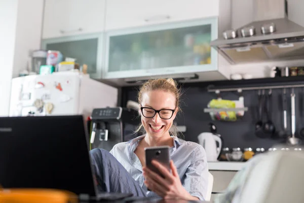 Restez à la maison et à distance sociale. Femme dans ses vêtements de maison occasionnels travaillant à distance de la table à manger de la cuisine. Chat vidéo sur les réseaux sociaux avec des amis, des membres de la famille, des entreprises ou des partenaires — Photo