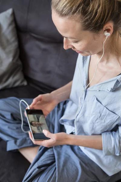 Kvinna hemma koppla av på soffan soffa med hjälp av sociala medier på telefon för video chatta med sina nära och kära under corona virus pandemi. Stanna hemma, social distanserande livsstil. — Stockfoto