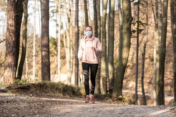 Le virus Corona, ou Covid-19, se propage dans le monde entier. Portrait de femme sportive caucasienne portant un masque de protection médicale tout en courant dans la nature . — Photo