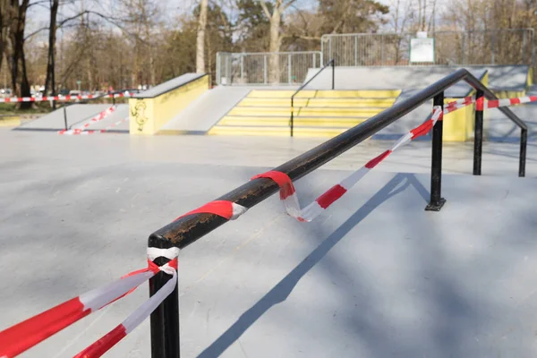 Restricción del virus Corona COVID-19. No hay gente por cuarentena. Parque de skate urbano cerrado. Parque vacío y parque infantil. Quédate en casa compaign. Cinta de advertencia roja en rampas y toboganes. Distanciamiento social — Foto de Stock