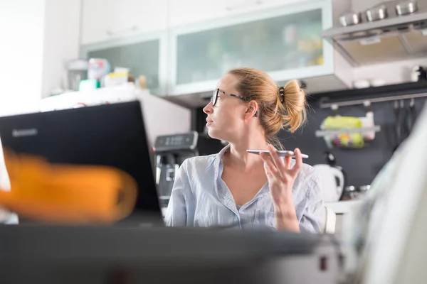 Quédate en casa y distanciamiento social. Mujer en su ropa casera informal trabajando remotamente desde su mesa de comedor de la cocina por la mañana. Chat de vídeo con amigos, familiares o clientes o socios comerciales —  Fotos de Stock