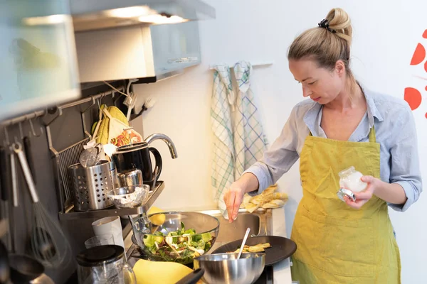待在家里，家庭主妇在厨房做饭，用平底锅腌菜，为家人做饭. — 图库照片