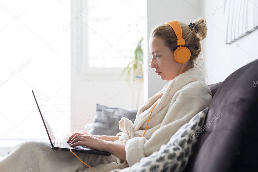 Stay at home and social distancing. Woman in her casual home bathrobe working remotly from her living room. Video chatting using social media with friend, family, business clients or partners