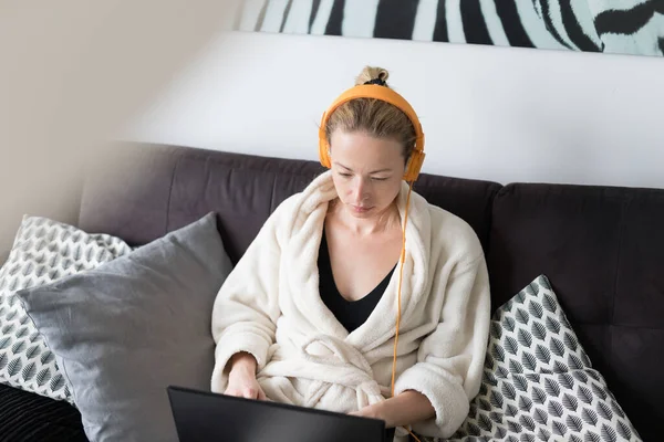 Thuis blijven, beschutting bieden en sociale afstand nemen. Vrouw in haar casual huisbadjas ontspannen tijdens het werken op afstand van haar woonkamer. Social media apps gebruiken voor videochatten. — Stockfoto