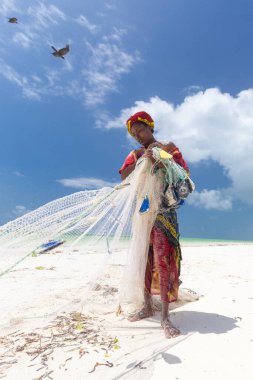 Paje sahilinde, Zanzibar, Tanzanya 'da geleneksel Afrika yerel balıkçılığı. Geleneksel giyinmiş yerel bir kadın balık ağı çekiyor, küçük balıkları yakalıyor..