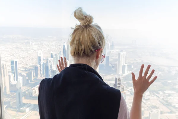 Dünyanın en yüksek gökdeleninin tepesindeki gözlem platformundan şehrin manzarasına hayran olan güzel kız, Dubai, BAE 'deki Burj Halife.. — Stok fotoğraf