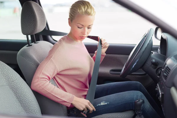 Beautiful woman fastening seat belt in small personal car. — Stock Photo, Image