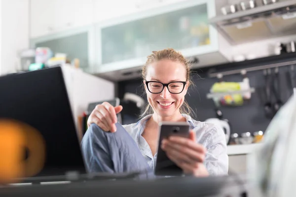 Restez à la maison et à distance sociale. Femme dans ses vêtements de maison occasionnels travaillant à distance de la table à manger de la cuisine. Chat vidéo sur les réseaux sociaux avec des amis, des membres de la famille, des entreprises ou des partenaires — Photo