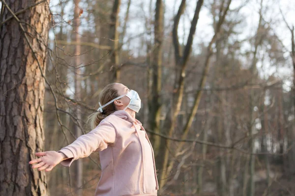 Retrato de mulher esportiva caucasiana usando máscara facial de proteção médica enquanto relaxa respirando fundo na floresta. Corona vírus, ou Covid-19, está se espalhando por todo o mundo — Fotografia de Stock