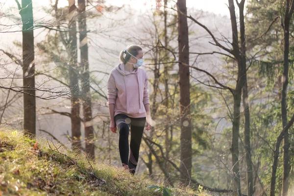 코로나 바이러스 (Covid-19) 는 전 세계로 확산되고 있다. 의학적 보호를 받고 숲 속을 걸어 다닐 때 얼굴에 마스크를 쓰고 있는 인큐베이터 여성의 모습. 코로나 바이러스. — 스톡 사진