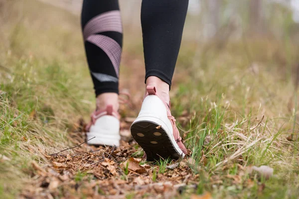 Rear close-up zicht van vrouwelijke stap op de natuur spoor. Jonge vrouw wandelen in de natuur. Avontuur, sport en lichaamsbeweging — Stockfoto