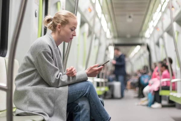 Porträtt av härlig flicka skriva meddelande på mobiltelefon i nästan tomma offentliga tunnelbanan tåg. Vistelse i hemmet och socialt avståndstagande rekomenderat på grund av koronaviruspandemi utbrott — Stockfoto