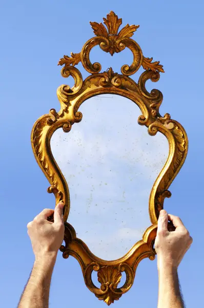 Hands holding mirror against the sky