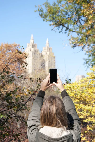 Young woman photographing The San Remo apartment from Central Park