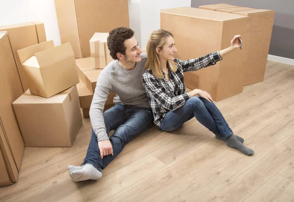 Happy young couple moving to new apartment taking selfie