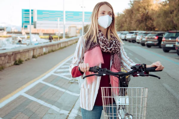 Young woman cycling and wearing protective mask