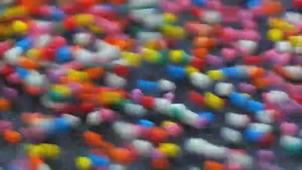 五彩斑斓的巨无霸灌满了甜糖糖的流动和封面镜头 下落和弹跳多种颜色的圆形颗粒 红龙相机慢动作镜头 — 图库视频影像